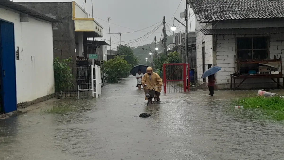 Di tengah banjir yang merendam jalan seorang bapak tetap mengayuh sepedanya
