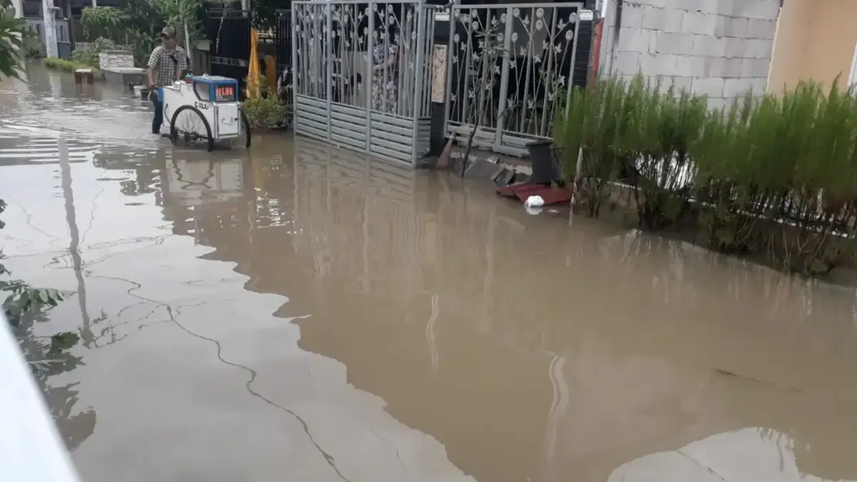 Warga Puri Nirwana Residence memancing lele di tengah banjir yang merendam permukiman.