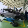 Teknisi melakukan proses spooring dan balancing pada sebuah mobil di bengkel.