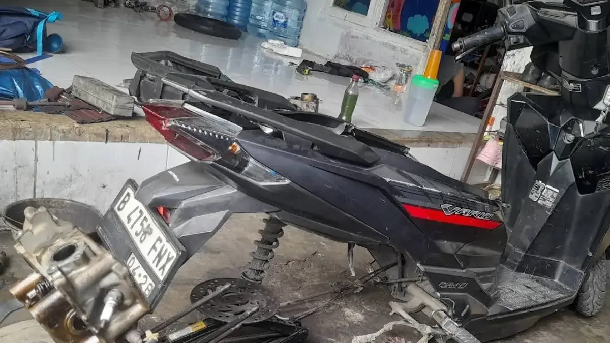 Aktivitas mekanik saat melakukan servis sepeda motor di bengkel umum.