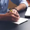 Ilustrasi fresh graduate mencari lowongan pekerjaan melalui laptop dan smartphone.