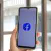 Ilustrasi pengguna membuka video di aplikasi Facebook melalui smartphone.
