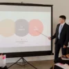Seorang profesional menyampaikan presentasi di hadapan klien dalam sebuah pertemuan bisnis.
